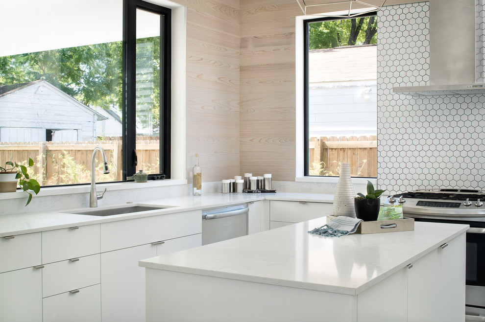 This is an example of a large contemporary l-shaped eat-in kitchen in Austin with an undermount sink, flat-panel cabinets, white cabinets, white splashback, mosaic tile splashback, stainless steel appliances, with island and solid surface benchtops.