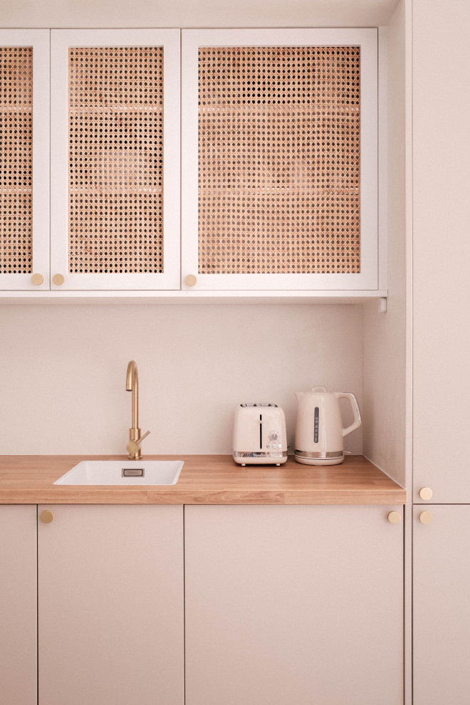 Offene, Einzeilige, Kleine Küche mit pinken Schränken, Arbeitsplatte aus Holz, Küchenrückwand in Beige und schwarzen Elektrogeräten in Paris