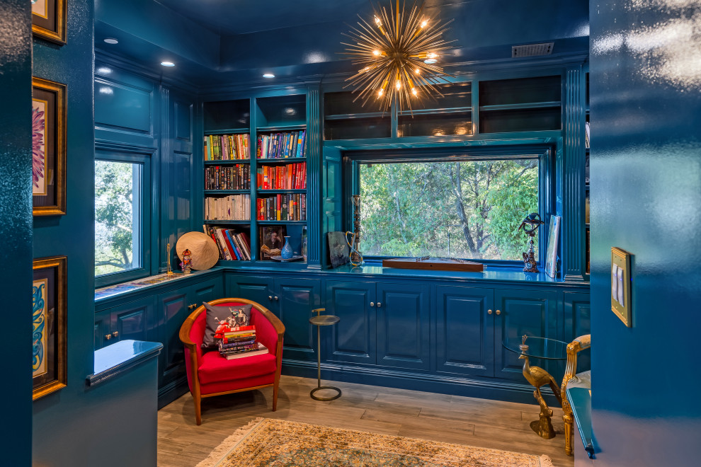 This is an example of a mid-sized mediterranean home office in San Francisco with a library, blue walls and a freestanding desk.
