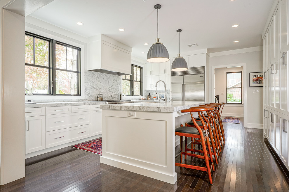 Design ideas for a traditional kitchen in Philadelphia with an undermount sink, shaker cabinets, white cabinets, grey splashback, stone slab splashback, stainless steel appliances, dark hardwood floors, with island, brown floor and grey benchtop.