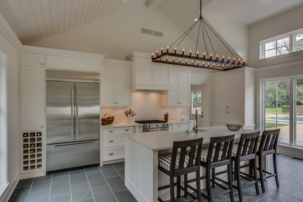 Mid-sized transitional u-shaped ceramic tile open concept kitchen photo in Chicago with a farmhouse sink, shaker cabinets, white cabinets, solid surface countertops, white backsplash, subway tile backsplash, stainless steel appliances and an island