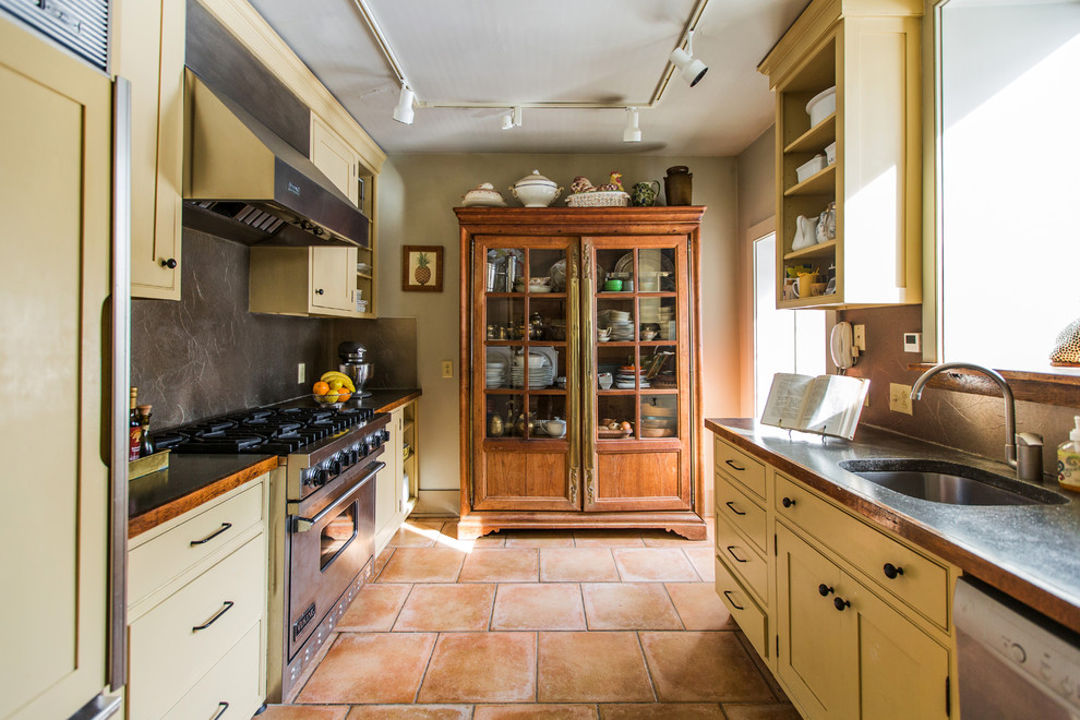 Inspiration for a mid-sized traditional galley separate kitchen in Philadelphia with an undermount sink, shaker cabinets, beige cabinets, copper benchtops, grey splashback, metal splashback, stainless steel appliances, terra-cotta floors, no island and red floor.