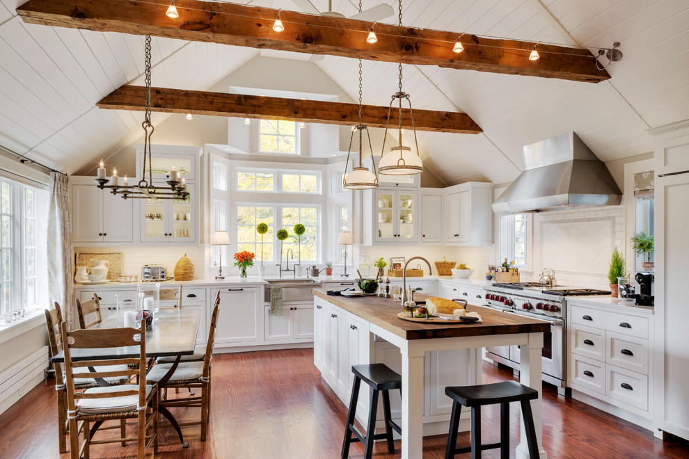 Design ideas for a traditional l-shaped eat-in kitchen in Boston with a farmhouse sink, shaker cabinets, white cabinets, white splashback, subway tile splashback, stainless steel appliances, medium hardwood floors and with island.