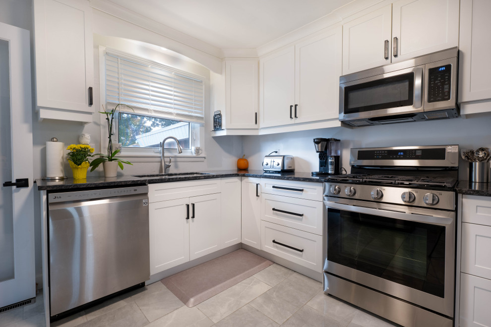 Small transitional l-shaped enclosed kitchen photo with a double-bowl sink, shaker cabinets, white cabinets, quartz countertops, stainless steel appliances, no island and black countertops