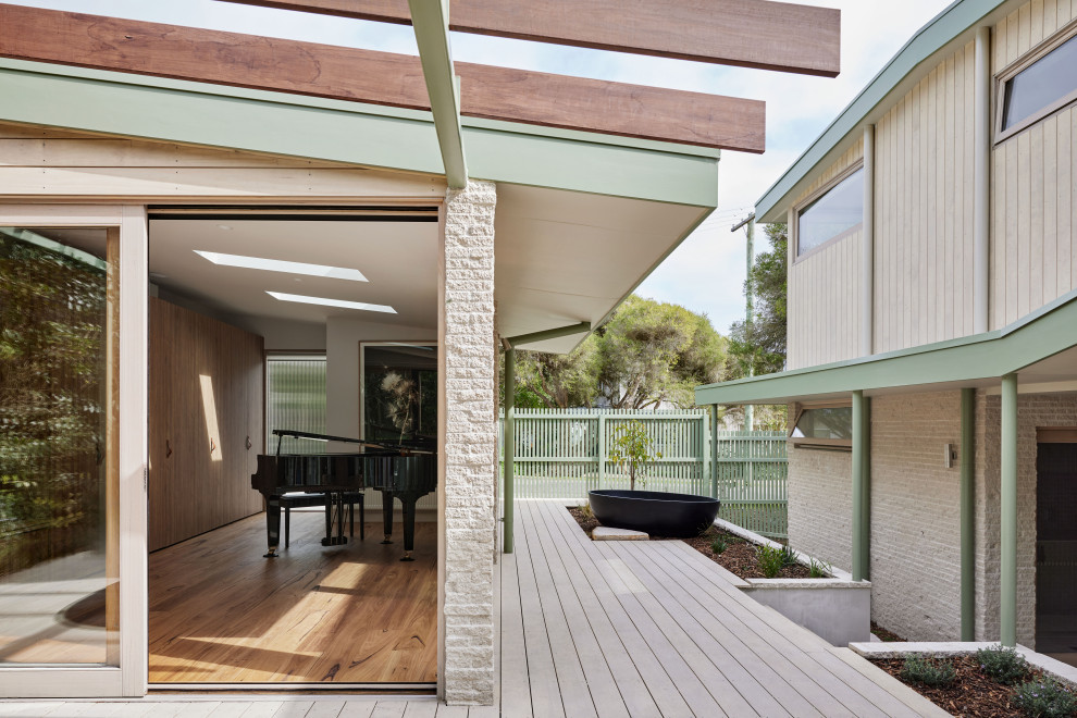 Inspiration for a mid-sized beach style courtyard and ground level deck in Melbourne with a container garden, a pergola and wood railing.