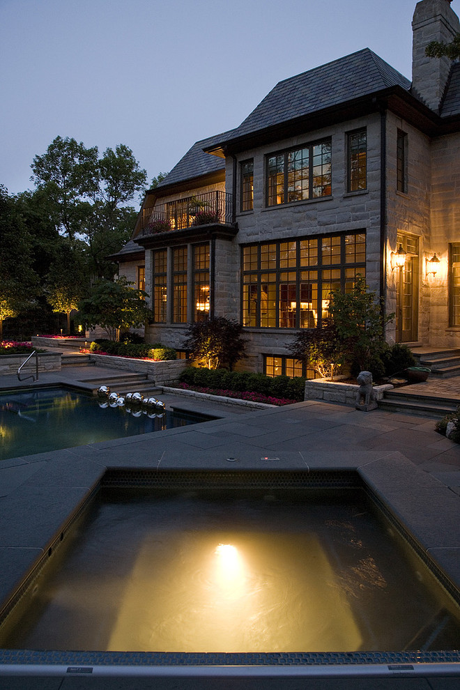 Photo of a large traditional backyard formal garden for summer in Chicago with a water feature and natural stone pavers.