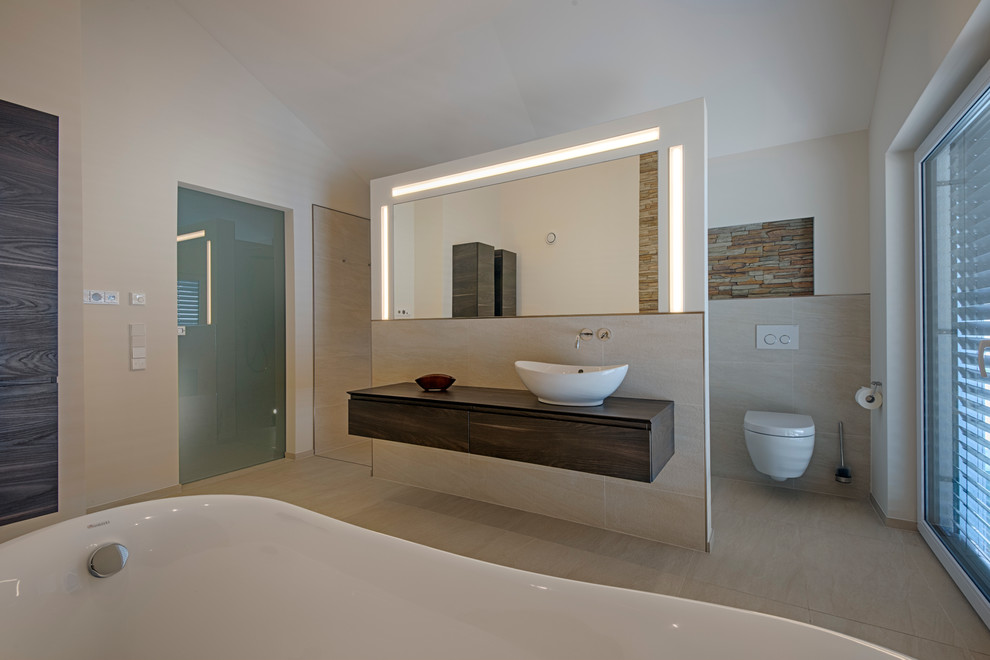 Badezimmer mit Aufsatzwaschbecken, flächenbündigen Schrankfronten, dunklen Holzschränken, Wandtoilette, weißer Wandfarbe und Steinwänden in Stuttgart