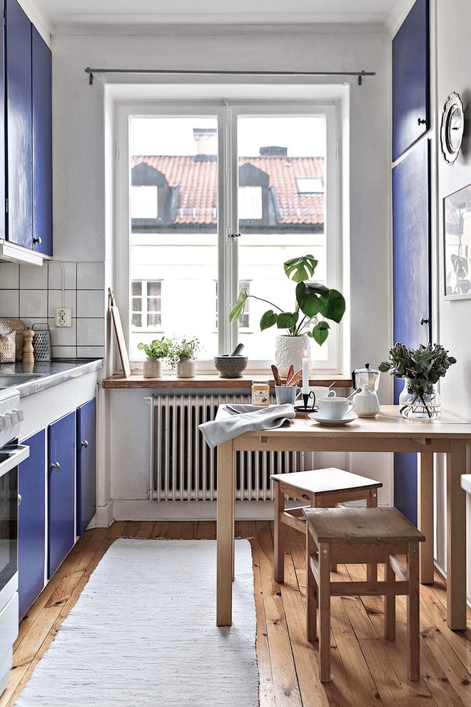 Inspiration for a scandinavian eat-in kitchen in Stockholm with flat-panel cabinets, zinc benchtops, white splashback and medium hardwood floors.
