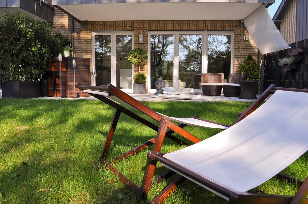 Mittelgroße Moderne Terrasse neben dem Haus, im Erdgeschoss mit Markisen und Feuerstelle in Sonstige