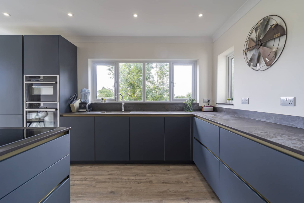 Inspiration for a large modern l-shaped open plan kitchen in Oxfordshire with an undermount sink, flat-panel cabinets, blue cabinets, black appliances, with island and brown benchtop.
