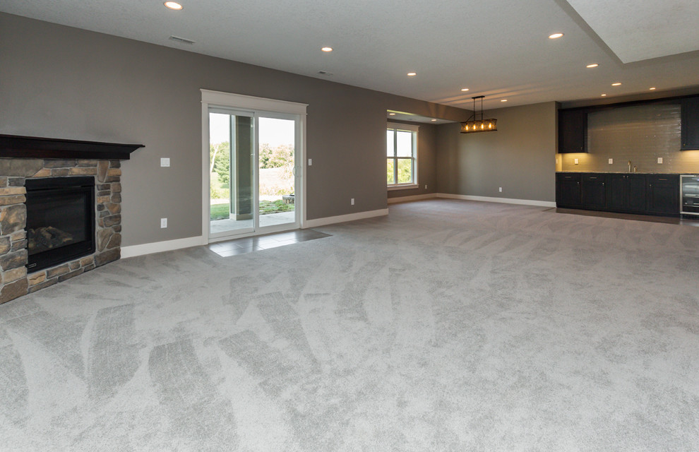 Inspiration for a large transitional walk-out carpeted basement remodel with gray walls, a corner fireplace and a stone fireplace