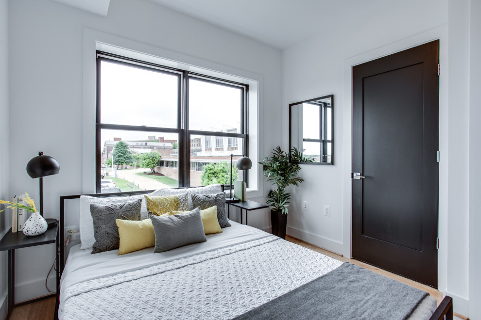 Inspiration for a contemporary bedroom in DC Metro with white walls, medium hardwood floors and brown floor.