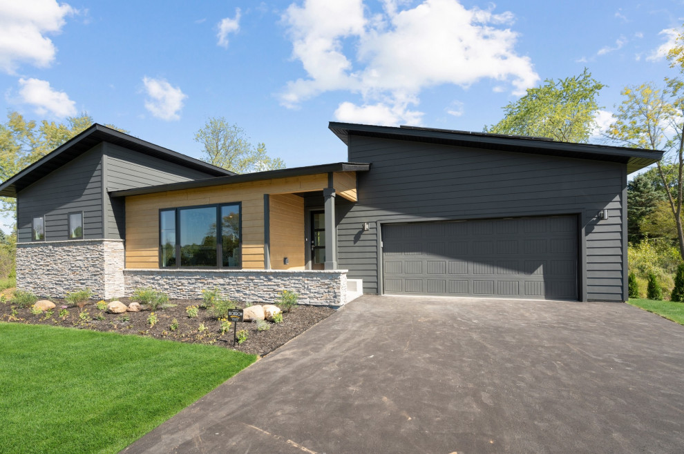 This is an example of a mid-sized modern two-storey black house exterior in Minneapolis with concrete fiberboard siding, a butterfly roof, a shingle roof, a black roof and clapboard siding.