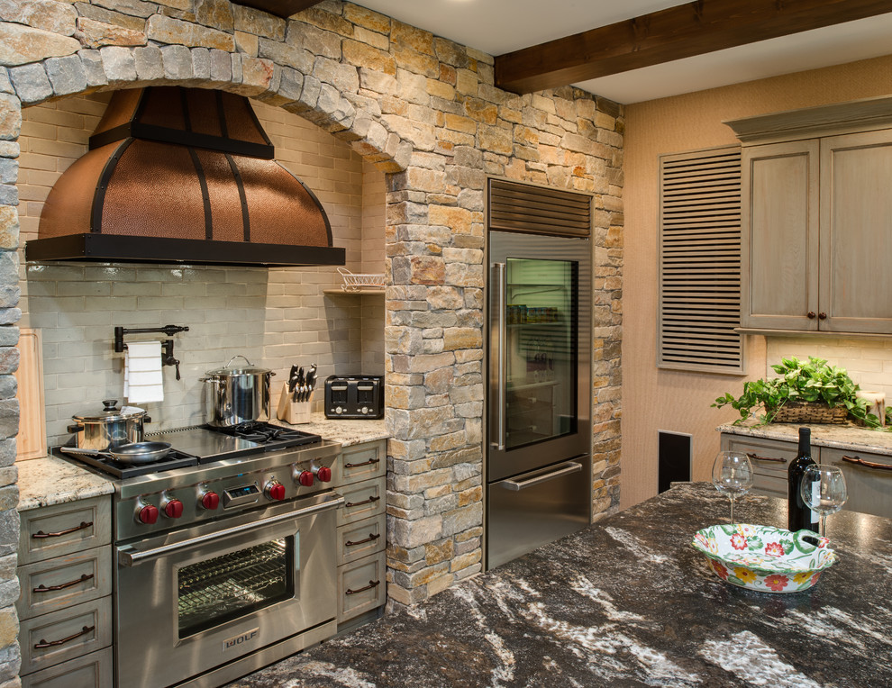 Example of a mountain style u-shaped concrete floor kitchen pantry design with a farmhouse sink, distressed cabinets, granite countertops, stainless steel appliances, white backsplash, subway tile backsplash, recessed-panel cabinets and an island