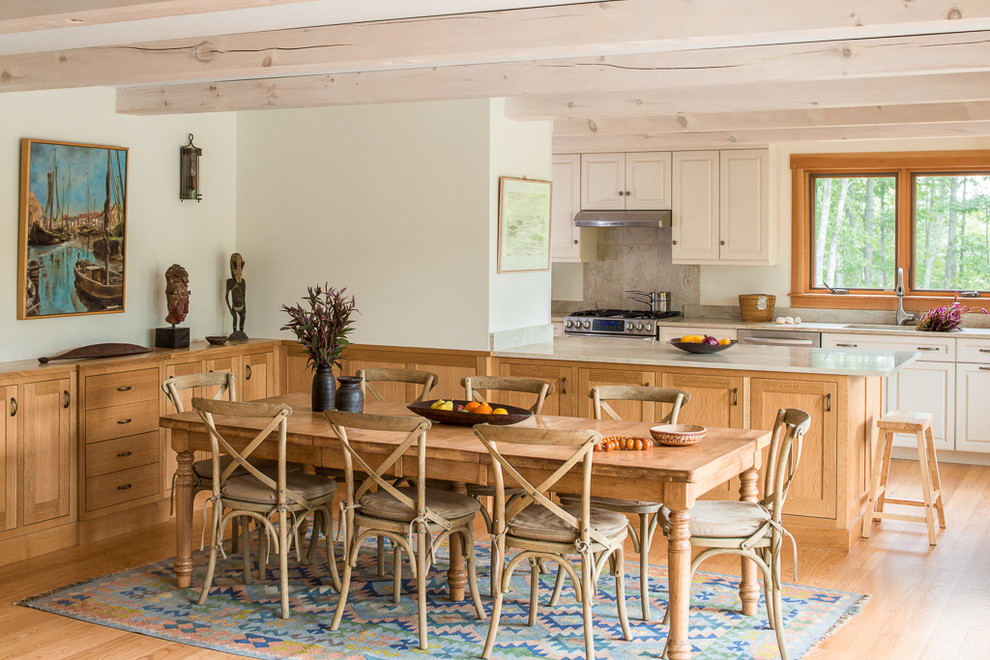 This is an example of a country kitchen/dining combo in Portland Maine with white walls and light hardwood floors.