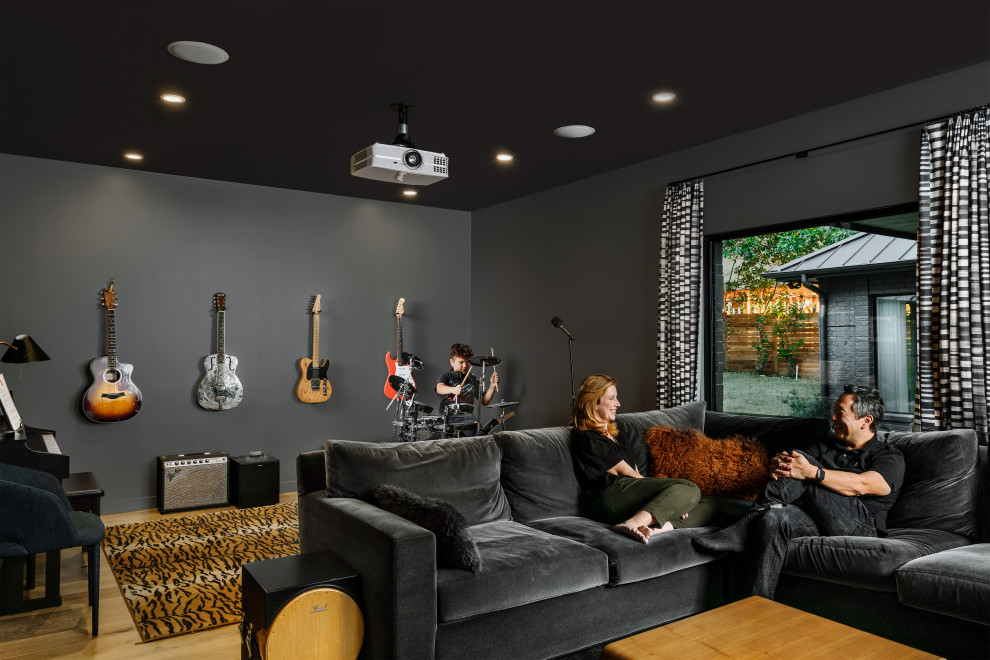Large contemporary enclosed family room in Austin with a music area, black walls, light hardwood floors, beige floor, timber and planked wall panelling.