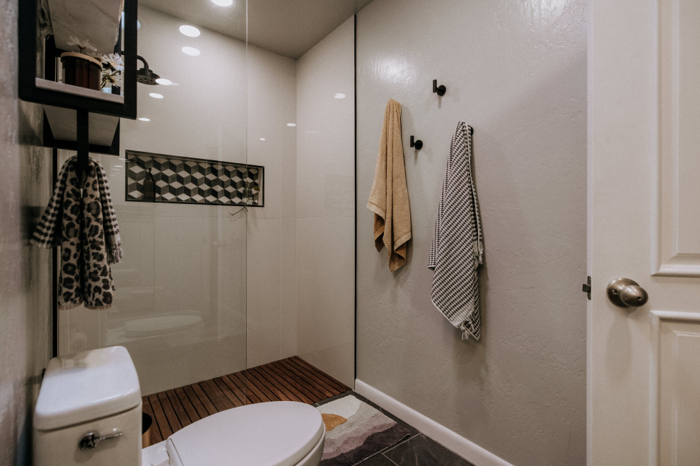 Inredning av ett 50 tals litet flerfärgad flerfärgat badrum med dusch, med möbel-liknande, skåp i ljust trä, en kantlös dusch, en toalettstol med hel cisternkåpa, vit kakel, porslinskakel, vita väggar, klinkergolv i keramik, ett undermonterad handfat, bänkskiva i terrazo, grått golv och med dusch som är öppen