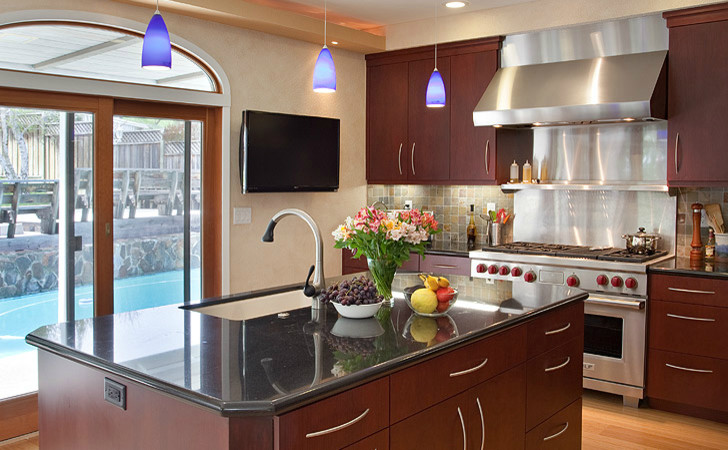 Example of a mid-sized minimalist l-shaped light wood floor eat-in kitchen design with a drop-in sink, medium tone wood cabinets, stainless steel appliances, an island, beige backsplash, flat-panel cabinets, granite countertops and cement tile backsplash