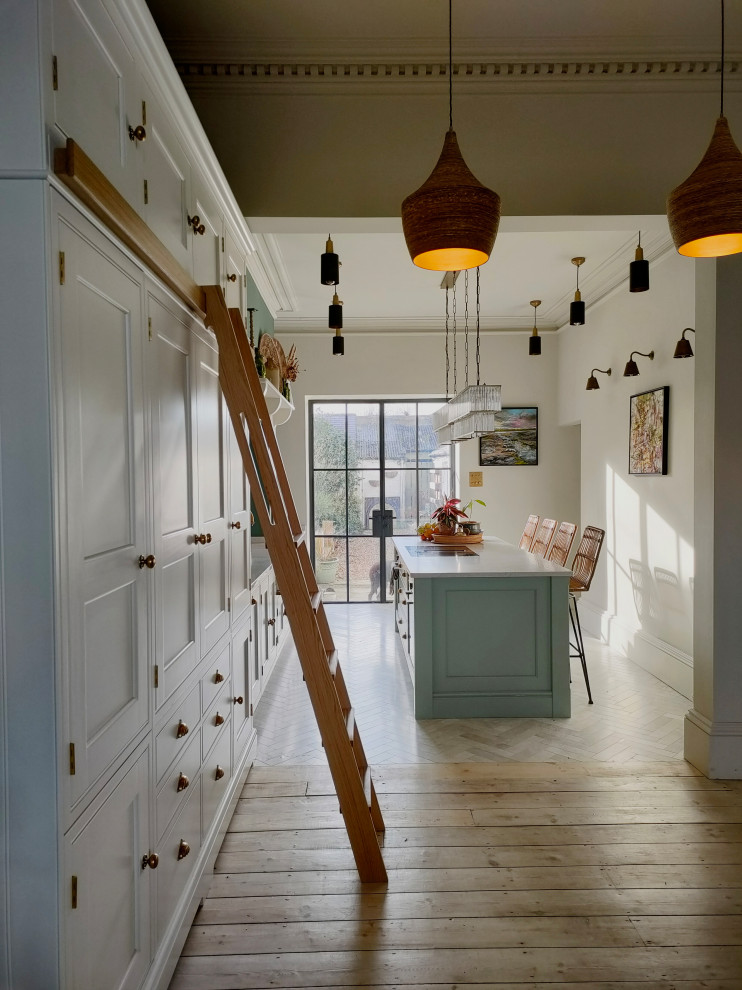 Mid-sized arts and crafts single-wall eat-in kitchen in Other with a farmhouse sink, shaker cabinets, white cabinets, granite benchtops, pink splashback, porcelain splashback, black appliances, marble floors, with island, white floor and pink benchtop.