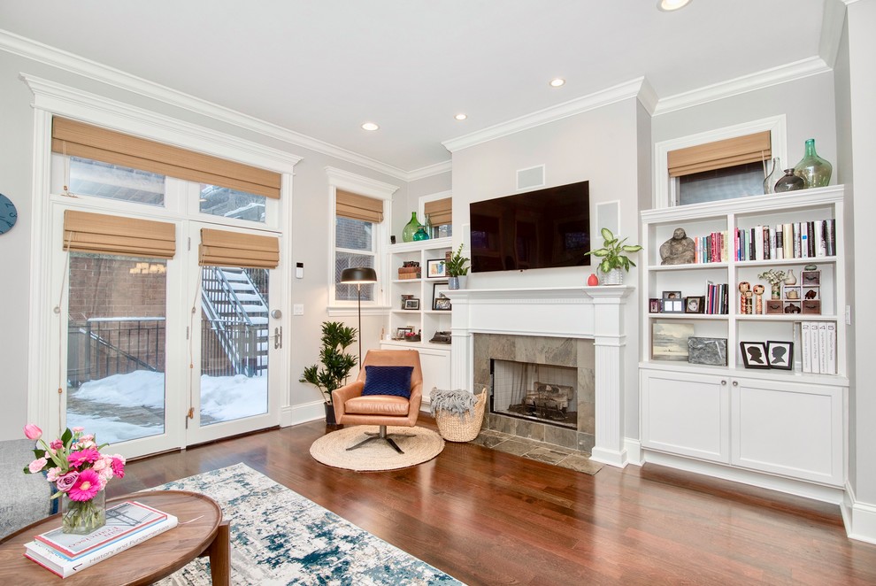 Mid-sized transitional enclosed family room in Providence with a library, grey walls, dark hardwood floors, a standard fireplace, a tile fireplace surround, a wall-mounted tv and brown floor.