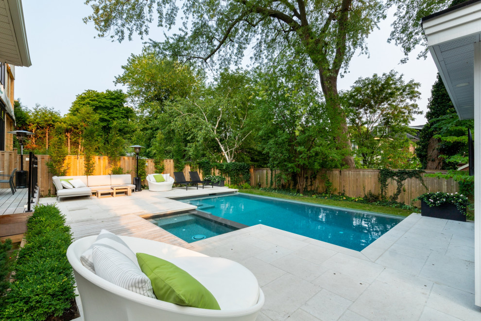 Photo of a small classic back rectangular infinity swimming pool in Toronto with with pool landscaping and natural stone paving.