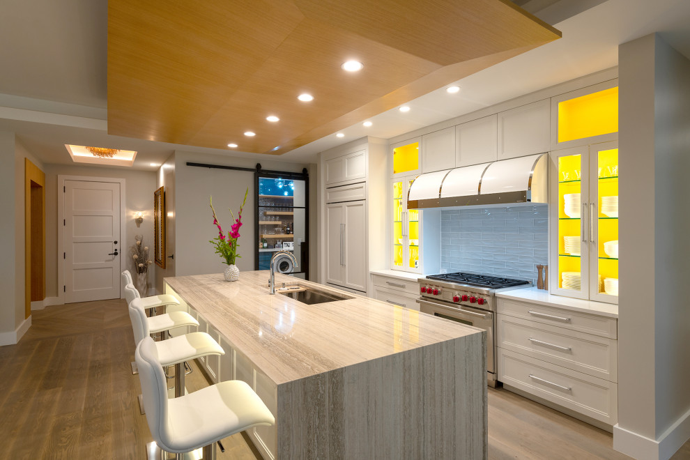 Transitional single-wall kitchen photo in Dallas with an undermount sink, shaker cabinets, white cabinets, limestone countertops, blue backsplash, glass tile backsplash, stainless steel appliances and an island
