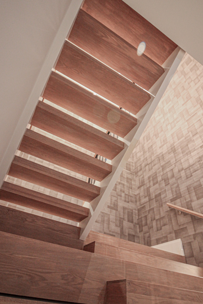 Large modern wood u-shaped staircase in DC Metro with wood risers, metal railing and wallpaper.