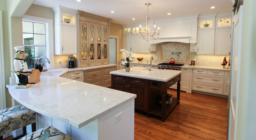 Exempel på ett avskilt, stort klassiskt vit vitt u-kök, med en undermonterad diskho, skåp i shakerstil, vita skåp, bänkskiva i kvarts, beige stänkskydd, stänkskydd i marmor, integrerade vitvaror, mellanmörkt trägolv, en köksö och brunt golv