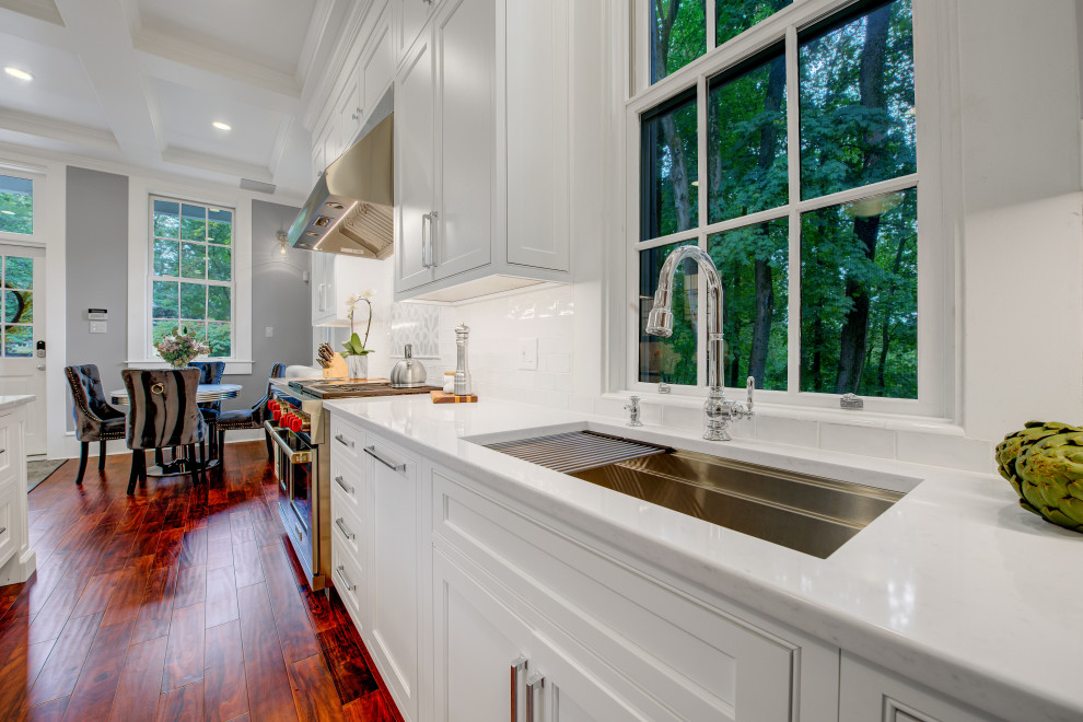 Design ideas for a large traditional galley eat-in kitchen in Philadelphia with an undermount sink, beaded inset cabinets, white cabinets, quartz benchtops, white splashback, porcelain splashback, medium hardwood floors, with island, brown floor, white benchtop and coffered.
