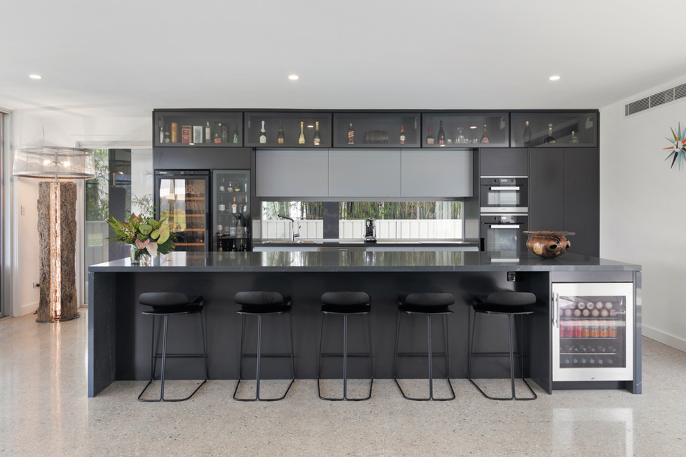 Photo of a large contemporary galley separate kitchen in Wollongong with black cabinets, with island, flat-panel cabinets, black appliances, beige floor and black benchtop.