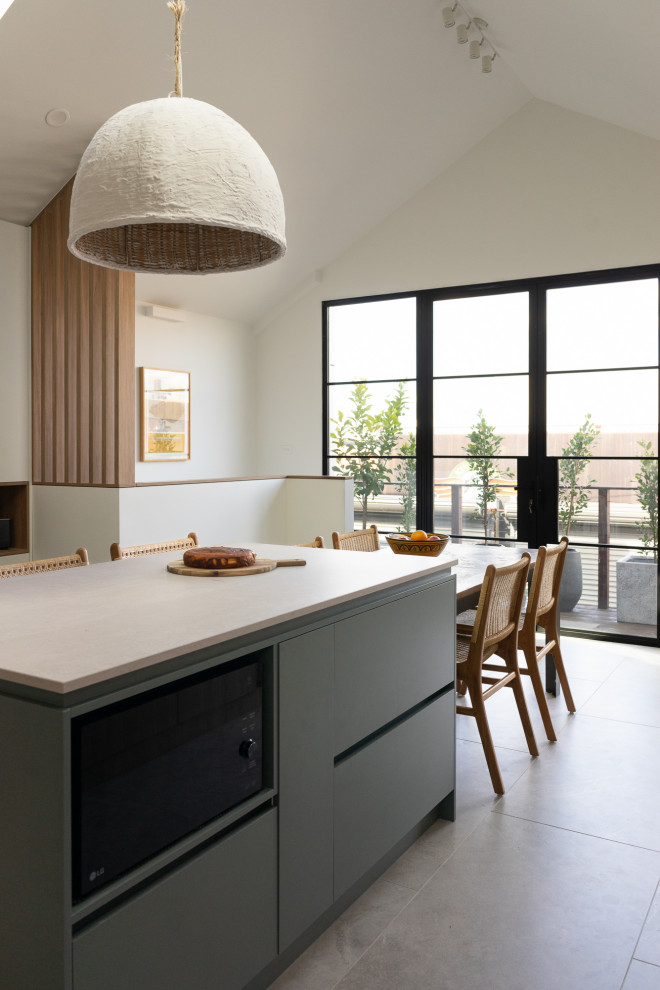 Photo of a mid-sized modern eat-in kitchen in Melbourne with an undermount sink, flat-panel cabinets, green cabinets, ceramic splashback, stainless steel appliances, porcelain floors, grey floor, grey benchtop and vaulted.