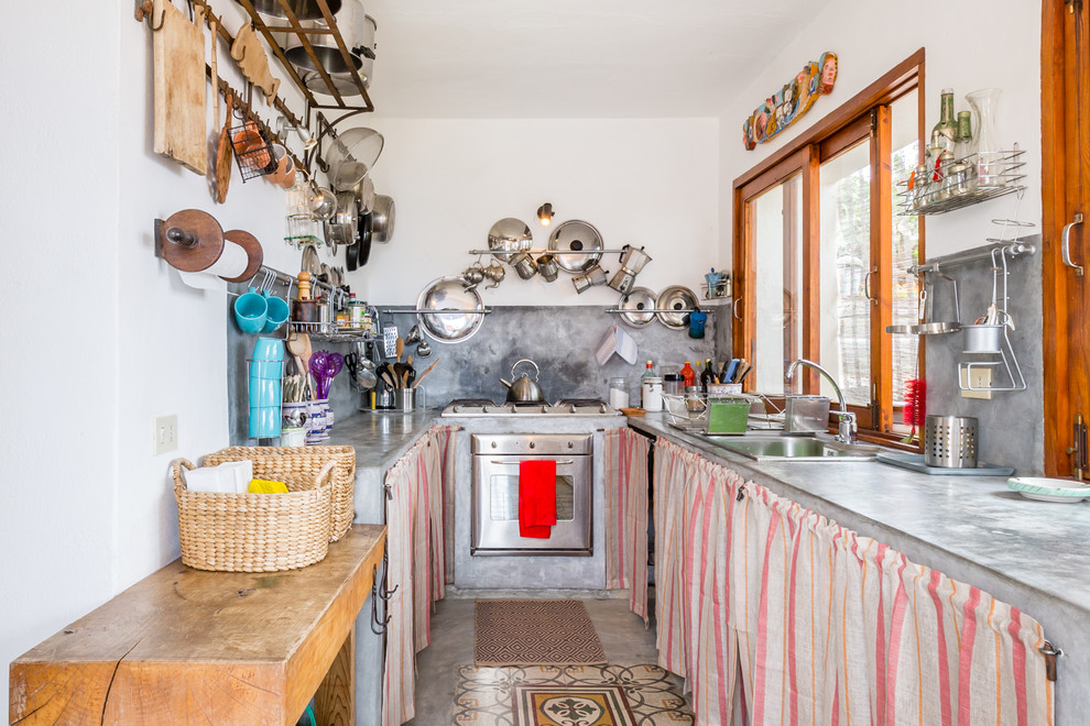Inspiration for a mid-sized mediterranean u-shaped separate kitchen in Other with a drop-in sink, open cabinets, concrete benchtops, grey splashback, stainless steel appliances, concrete floors, grey floor and no island.