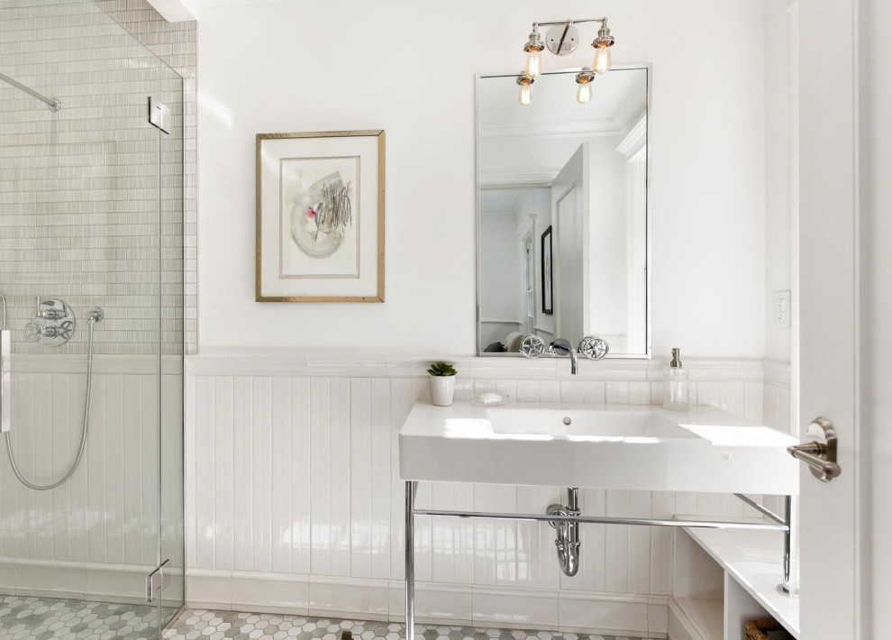 Foto på ett mellanstort vintage vit badrum med dusch, med en kantlös dusch, en toalettstol med hel cisternkåpa, vit kakel, tunnelbanekakel, vita väggar, mosaikgolv, ett konsol handfat, marmorbänkskiva, flerfärgat golv, dusch med gångjärnsdörr och öppna hyllor