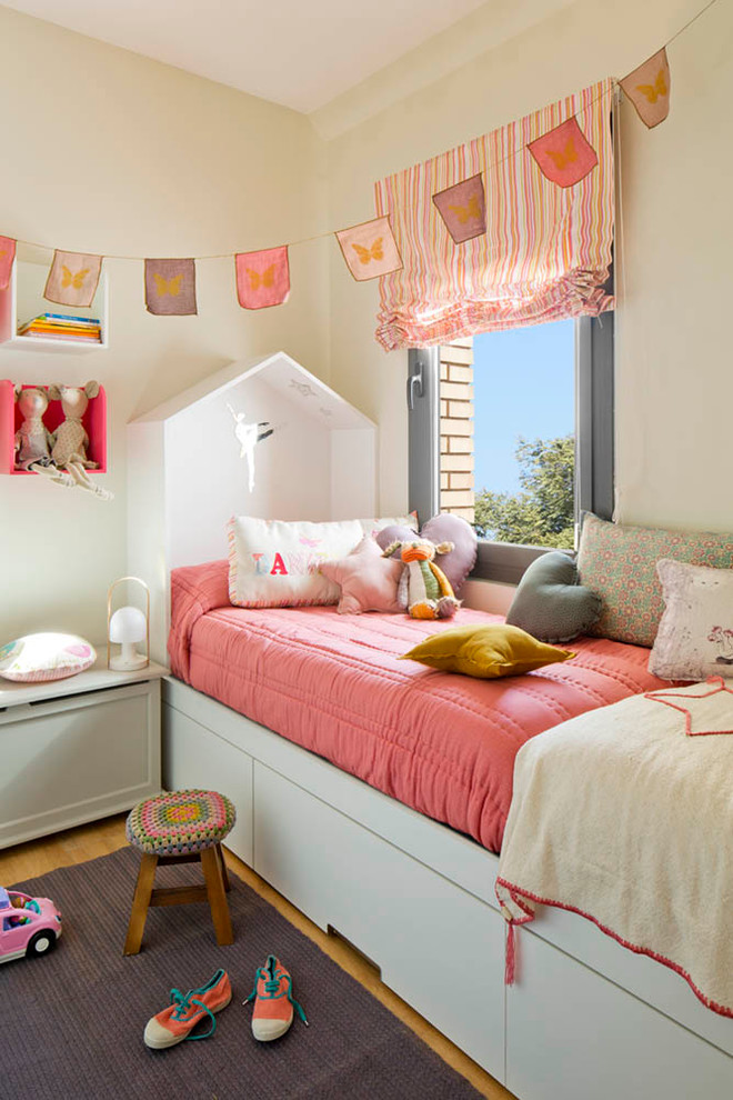 This is an example of a small contemporary kids' room for girls in Barcelona with white walls and light hardwood floors.