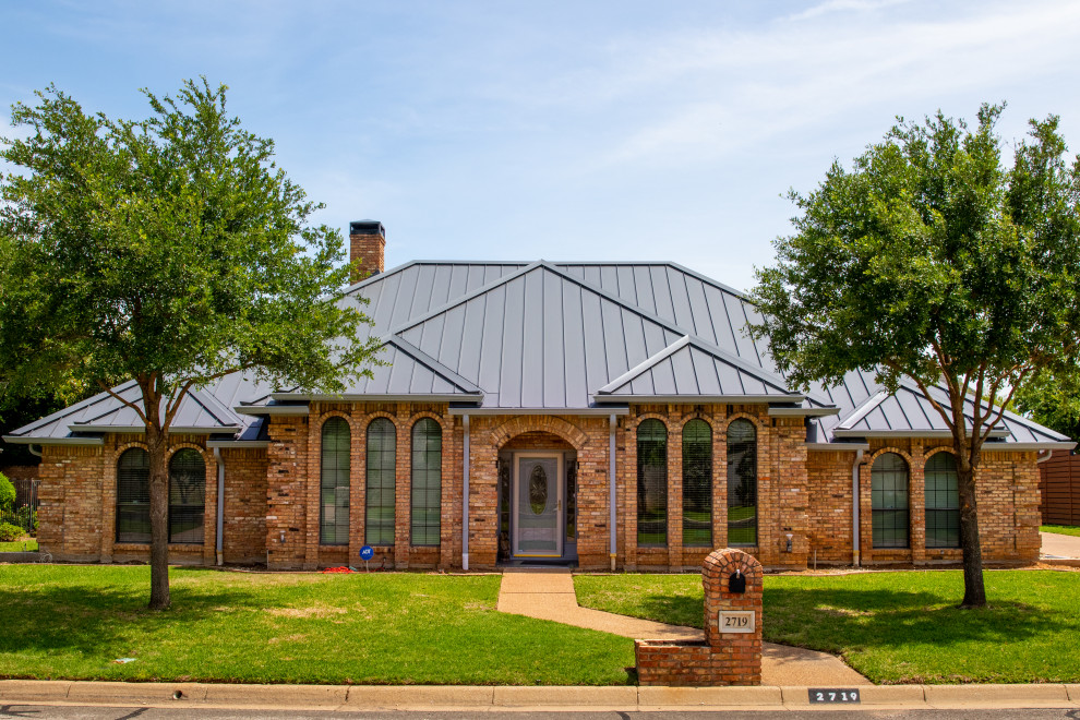 Design ideas for a mid-sized one-storey brick house exterior in Dallas with a metal roof.