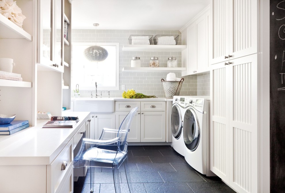 Design ideas for a mid-sized traditional l-shaped utility room in San Francisco with quartz benchtops, a farmhouse sink, shaker cabinets, white cabinets, a side-by-side washer and dryer, black floor and white benchtop.