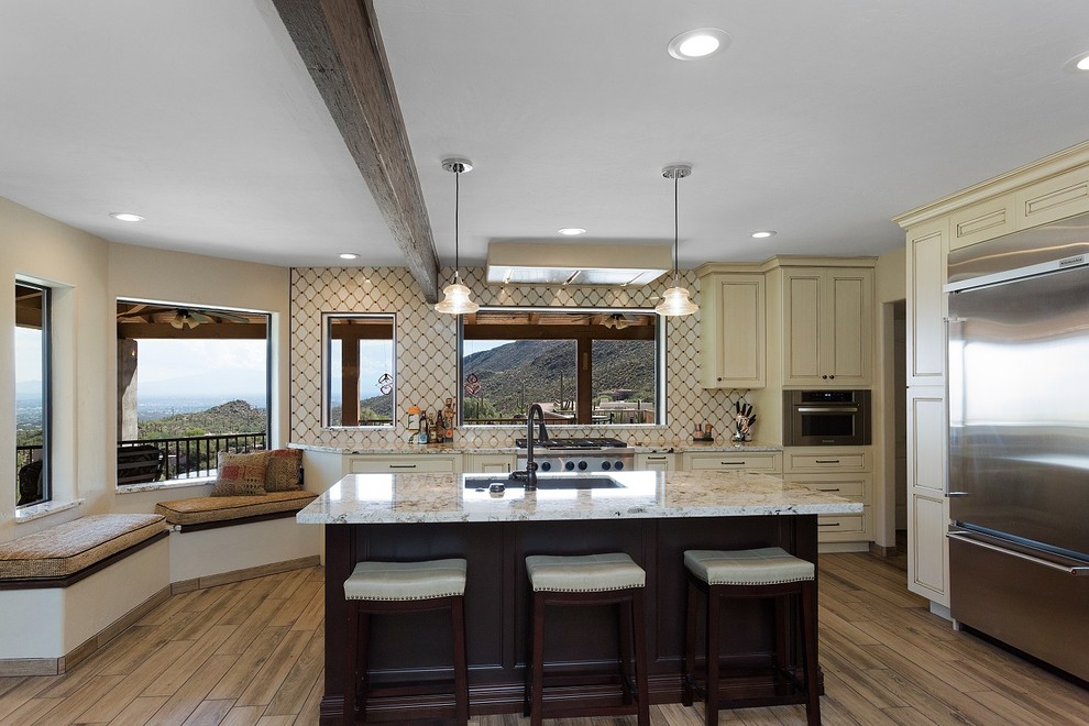 Open concept kitchen - large transitional l-shaped porcelain tile and brown floor open concept kitchen idea in Phoenix with an undermount sink, recessed-panel cabinets, dark wood cabinets, granite countertops, beige backsplash, ceramic backsplash, stainless steel appliances, an island and beige countertops