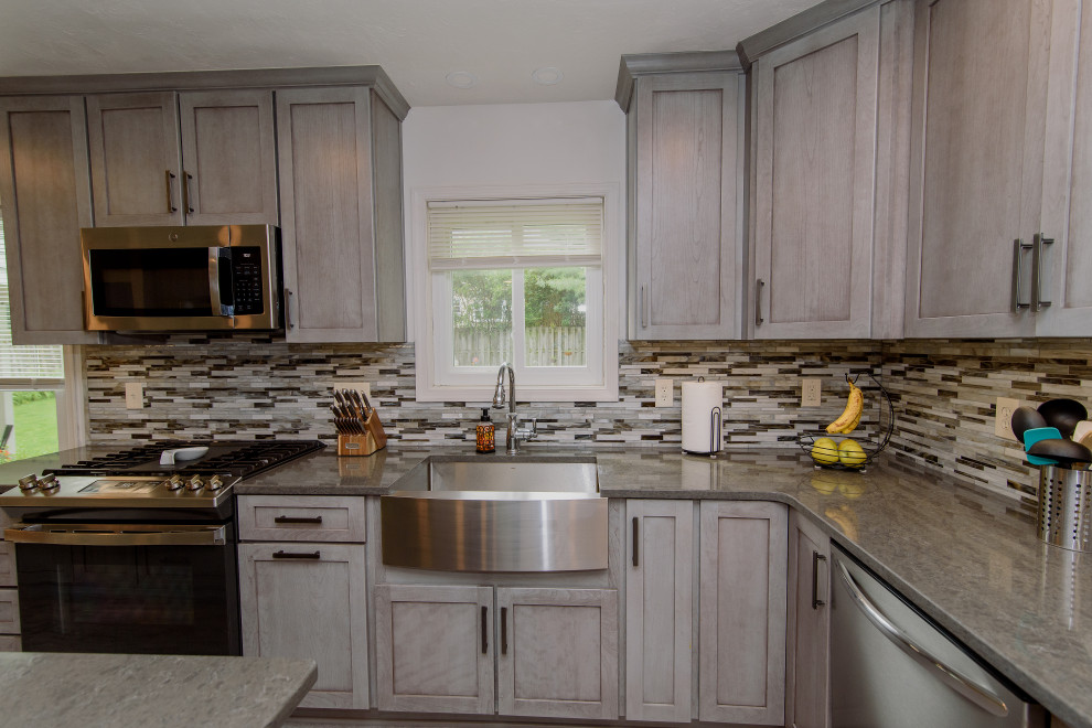 Inspiration for a large transitional u-shaped gray floor eat-in kitchen remodel in Baltimore with a farmhouse sink, shaker cabinets, gray cabinets, quartz countertops, multicolored backsplash, glass tile backsplash, stainless steel appliances, an island and gray countertops