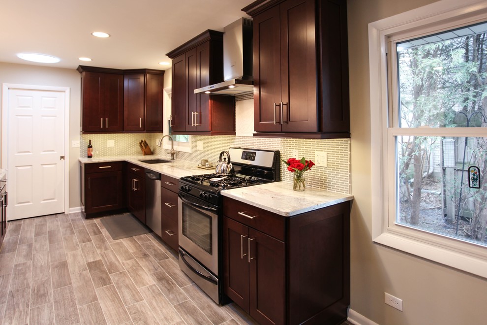 Large transitional u-shaped porcelain tile eat-in kitchen photo in Chicago with an undermount sink, recessed-panel cabinets, dark wood cabinets, granite countertops, gray backsplash, glass tile backsplash, stainless steel appliances and an island