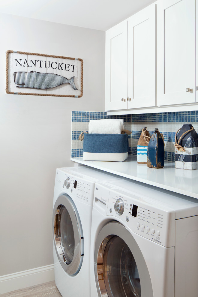 This is an example of a small beach style single-wall dedicated laundry room in Miami with shaker cabinets, white cabinets, wood benchtops, white walls, porcelain floors, a side-by-side washer and dryer and white benchtop.