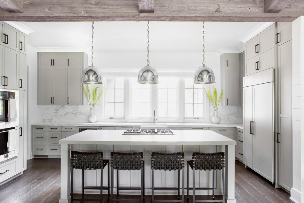 Inspiration for a mid-sized country u-shaped kitchen in New York with a farmhouse sink, shaker cabinets, grey cabinets, white splashback, marble splashback, panelled appliances, dark hardwood floors, with island and white benchtop.