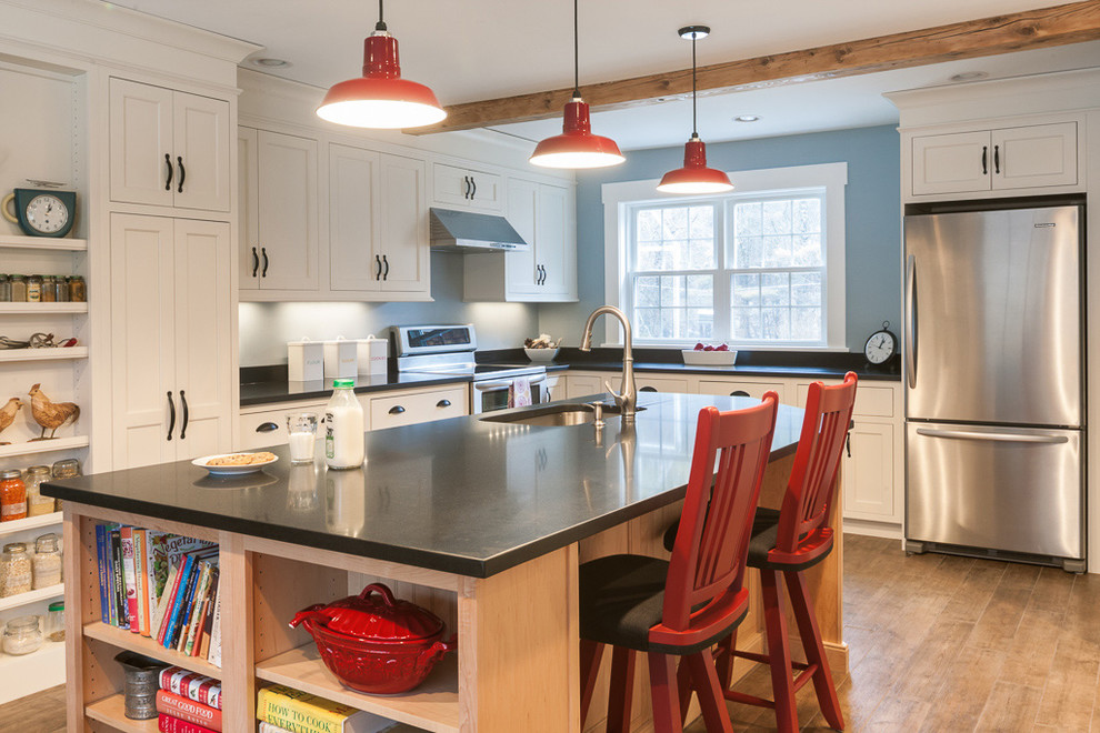 Photo of a country l-shaped kitchen in Portland Maine with an undermount sink, shaker cabinets, white cabinets, stainless steel appliances, granite benchtops, black splashback and stone slab splashback.