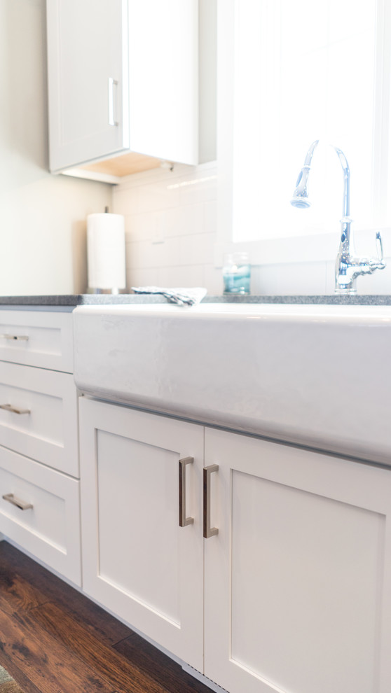 Inspiration for a large transitional u-shaped eat-in kitchen remodel with a farmhouse sink, flat-panel cabinets, white cabinets, granite countertops, white backsplash, ceramic backsplash, stainless steel appliances and an island