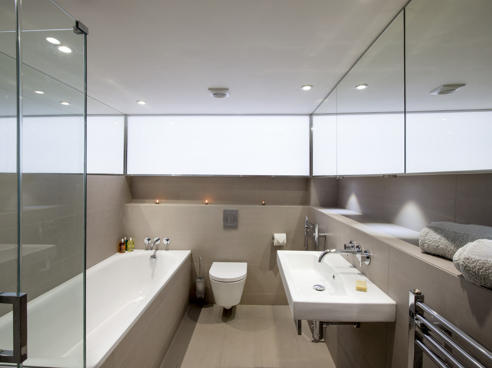 This is an example of a contemporary bathroom in London with a wall-mount sink, an alcove tub and a wall-mount toilet.