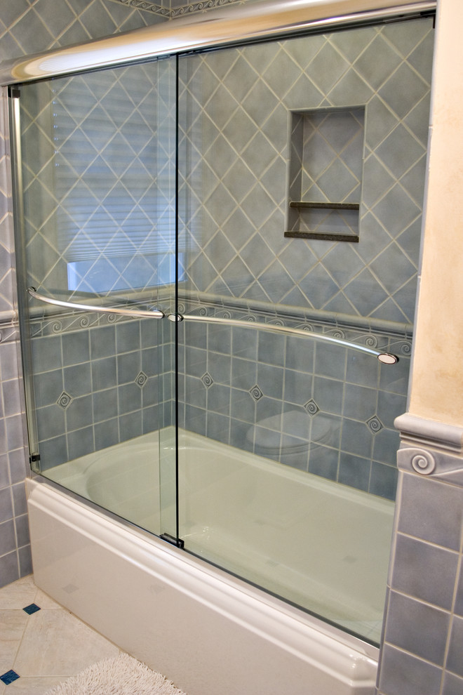 Photo of a small coastal bathroom in Bridgeport with a submerged sink, freestanding cabinets, distressed cabinets, granite worktops, an alcove bath, a shower/bath combination, a two-piece toilet, blue tiles, porcelain tiles, beige walls and porcelain flooring.