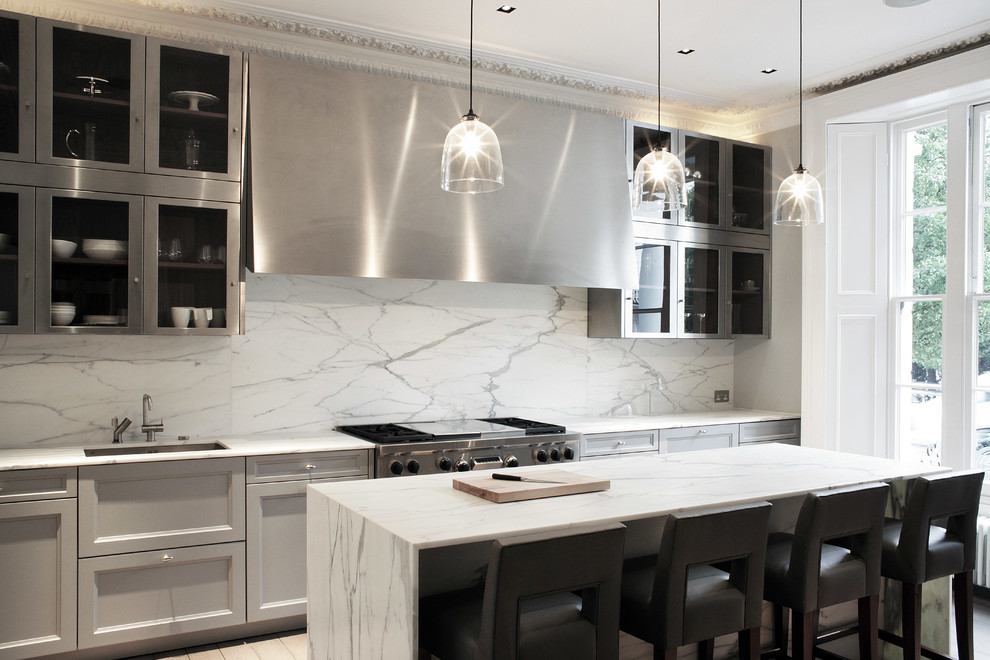 Design ideas for a transitional kitchen in London with an undermount sink, glass-front cabinets, stainless steel cabinets, multi-coloured splashback, stainless steel appliances and with island.
