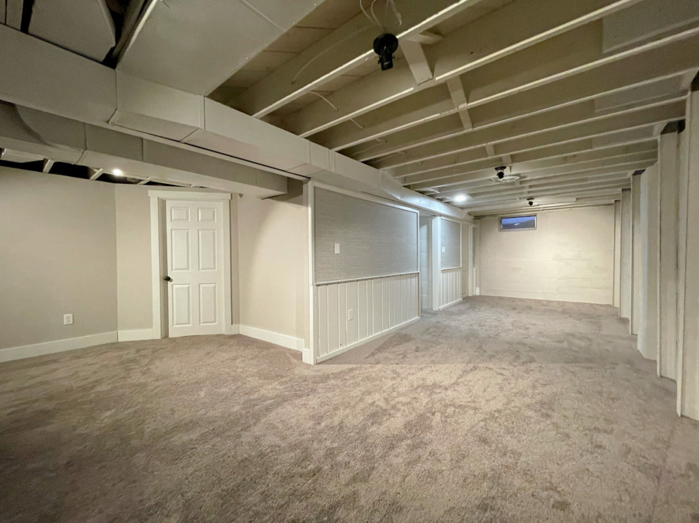 Design ideas for a mid-sized modern look-out basement in Detroit with grey walls, carpet, no fireplace, grey floor and exposed beam.