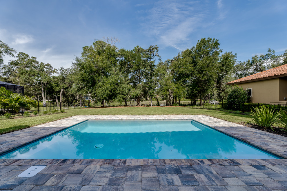 This is an example of a large mediterranean backyard rectangular pool in Jacksonville with concrete pavers.