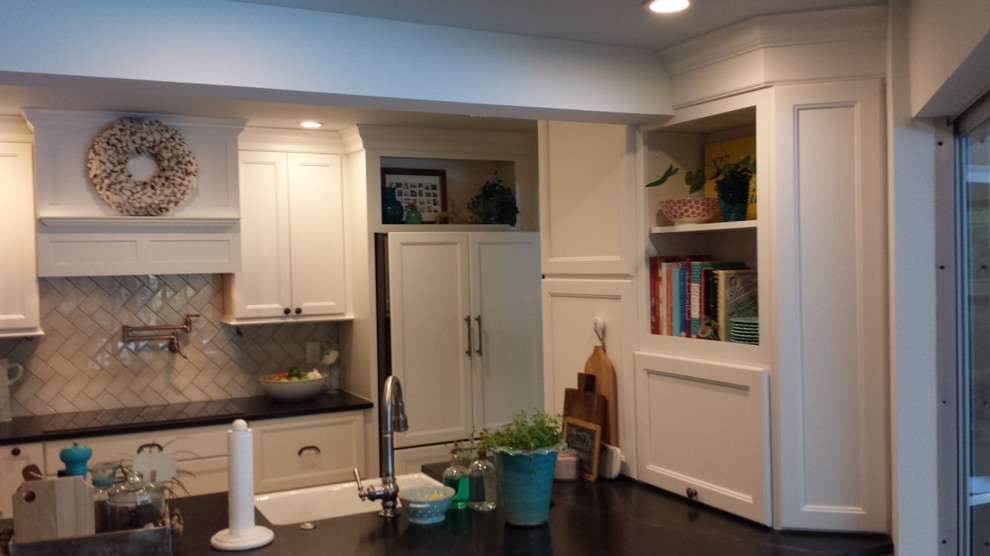 Example of a transitional galley kitchen design in Tampa with a farmhouse sink, recessed-panel cabinets, white cabinets, granite countertops, beige backsplash, glass tile backsplash and paneled appliances