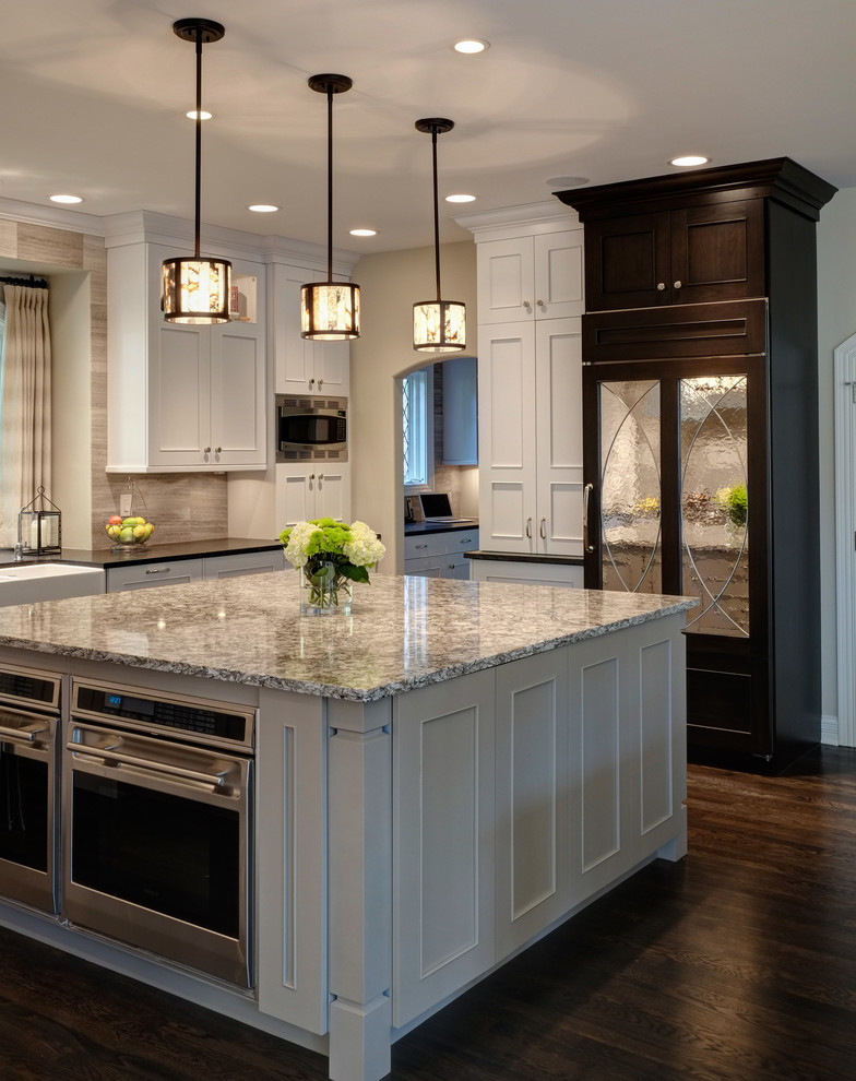 Transitional l-shaped kitchen photo in Chicago with a farmhouse sink, beige backsplash, stone tile backsplash and stainless steel appliances